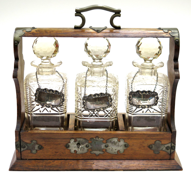 Tantalus, ek med mässingsbeslag, England, 1900-talets 1 hälft, innehåller 3 karaffer med propp i slipad kristall, medföljer 3 skyltar i sterlingsilver graverade "Whisky", "Brandy" respektive "Sherry"_1867a_8d84856f1ef75a5_lg.jpeg